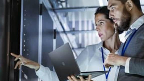 Two people using a laptop in a data centre