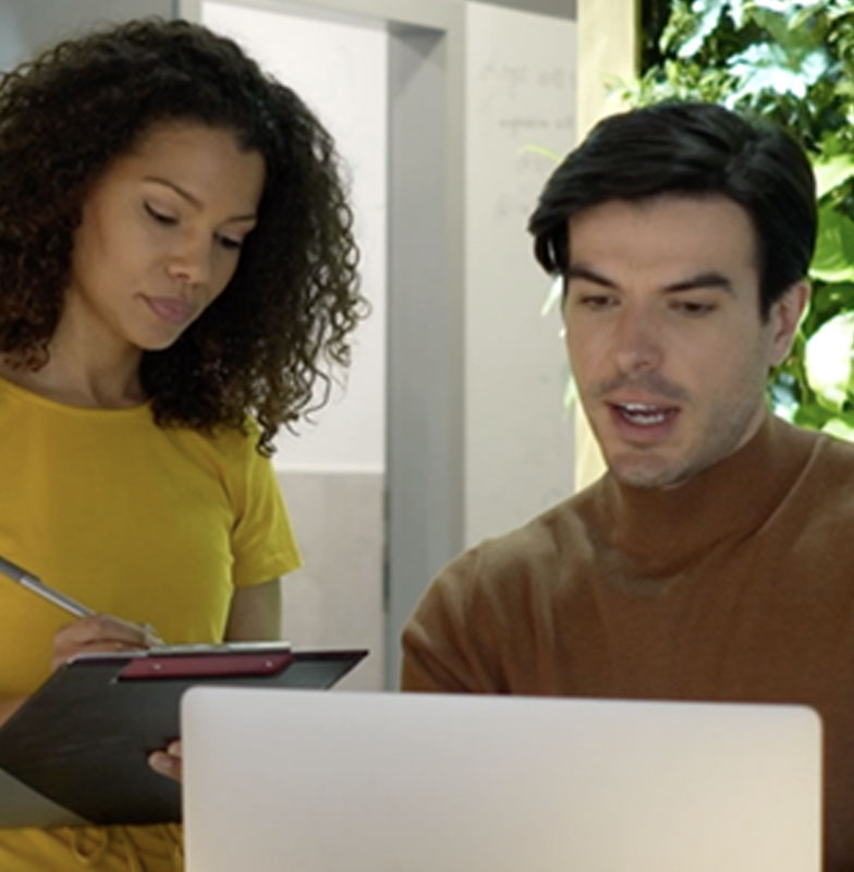 Two coworkers at a laptop.